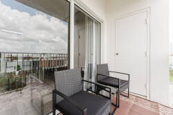 Step outside to your private balcony, where two sleek black chairs invite you to enjoy the fresh air. The expansive glass door allows natural light to flood in, creating a bright and airy atmosphere that enhances your stay.