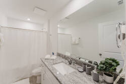This bright and airy bathroom features a sleek granite countertop and modern fixtures, with soft white tones and greenery that create a refreshing atmosphere, inviting you to relax after a day of adventure.