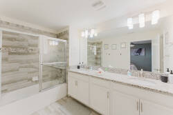Enjoy the spaciousness of this bright bathroom with sleek granite countertops and a modern glass-enclosed shower, all set in a neutral palette with stylish lighting for a clean, refreshing atmosphere during your stay.