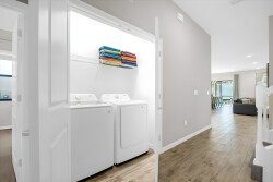 Enjoy a stylish laundry area featuring a modern washer and dryer, along with neatly stacked colorful towels. This bright space flows effortlessly into the living area, ensuring your comfort throughout your stay.