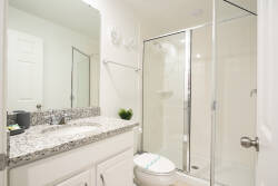 Enjoy a bright bathroom with a sleek glass shower and stylish granite countertop, creating a sophisticated yet refreshing atmosphere to help you start your day with confidence.