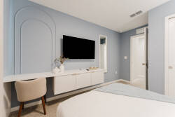 Enjoy this stylish bedroom with a calming blue accent wall, a modern desk, and a plush chair for relaxation or work. The wall-mounted TV and tasteful decor enhance the cozy atmosphere, making it perfect for unwinding.