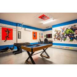 Enjoy a bold superhero-themed game room with foosball, pool table, arcade games, gaming chairs, and a wall-mounted TV. Colorful murals and bright blue accents create a fun space for kids, teens, and adults to play together.
