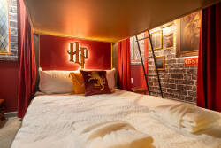 Experience a whimsical sanctuary that celebrates a magical world with rich burgundy walls, cozy bedding, and striking decor. Enjoy the warm lighting and playful artwork that create an immersive atmosphere for your stay.