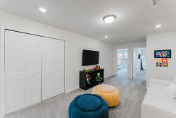 This cozy living area is bright and airy, featuring soft gray carpeting and playful blue and yellow bean bags. The sleek entertainment unit with a flat-screen TV invites you to unwind after a day of adventure.