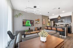 Relax in a spacious living area with a stunning geometric accent wall and stylish furnishings. Enjoy your favorite shows on the comfortable sofa while basking in natural light from the large windows.