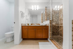 Bright and polished, this bathroom features a stylish wooden vanity paired with elegant tile accents. The walk-in shower, illuminated by modern lighting, adds a touch of luxury to your daily routine.