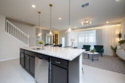 Enjoy a stylish kitchen featuring dark cabinetry and gorgeous granite countertops that seamlessly connect to a cozy living area. Pendant lights add warmth, while large windows bring in natural light for a welcoming atmosphere.
