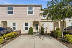 Arrive at a welcoming two-story townhome with a private driveway, bright exterior, white shutters, shaded entry, and fresh landscaping, creating a calm first impression for your vacation.