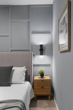 Rest in a modern bedroom with a cozy bed, gray accent wall, soft curtains, wall-mounted TV, warm wood nightstands, and gentle lighting, perfect for relaxing during vacation.