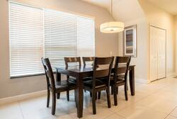 This inviting dining area features a sleek dark wood table and sturdy chairs, ideal for family meals or game nights. Natural light streams through the large window, highlighting the stylish pendant light above.