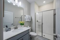 This bright bathroom boasts a sleek glass shower and a spacious vanity with elegant white countertops, ideal for your morning routine. Fresh yellow tulips add a cheerful touch, enhancing the clean, modern look of the space.