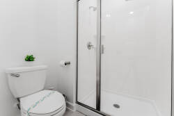 This bright bathroom features a sleek glass shower and modern fixtures, creating a fresh atmosphere. The minimalistic design, paired with a touch of greenery, enhances the sense of cleanliness and comfort for your stay.