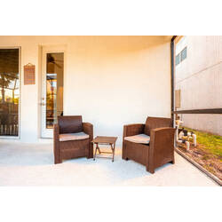 Relax in a cozy covered patio corner with two wicker chairs, a small table, and warm natural light. The screened enclosure and nearby glass doors create a quiet spot to enjoy coffee, conversation, or peaceful Florida evenings.