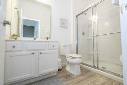 This bright and airy bathroom features a sleek walk-in shower with glass doors, enhancing the spacious feel. Soft cabinetry hues and natural light create a refreshing atmosphere, ideal for unwinding after a day of adventure.