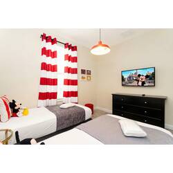Enjoy a cheerful Mickey-themed bedroom with two comfortable beds, red and white striped accents, character pillows, playful wall art, soft lighting, and cozy decor for kids.