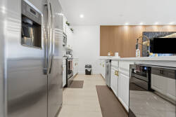 Discover a stylish kitchen featuring stainless steel appliances and chic cabinetry, designed for culinary adventures. The warm wooden accents and sleek countertops create a welcoming space ideal for shared meals and laughter.