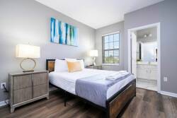 Welcome to this bright and airy bedroom featuring a comfortable bed, stylish nightstands, and soft lighting for a cozy feel. The large window brings in natural light, and tasteful art adds a charming touch to the decor.