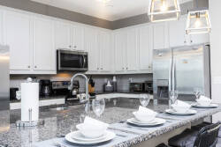 Experience a culinary haven with sleek white cabinetry and a beautiful granite countertop, ideal for meal prep or casual dining. Stylish pendant lighting above the island adds a contemporary flair to this inviting space.