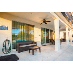 Enjoy a spacious covered lanai with wicker seating, ceiling fans, sliding glass doors, and an outdoor dining area. Warm sunlight and pool views create a comfortable space to relax, share meals, and enjoy Florida evenings