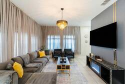 Experience a chic living room featuring soft gray sofas and lively yellow accents that create a warm atmosphere. Large windows with elegant curtains let in natural light, while a stunning chandelier elevates the space's elegance.