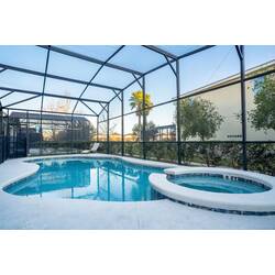 Relax in a private screened pool area with a sparkling pool, raised spa, and peaceful green views. Natural light, a lounge chair, and the airy enclosure create a calm spot to unwind after fun days in Orlando.