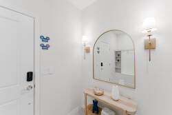 Welcome to a bright entryway featuring a stylish arched mirror and soft sconces that create a warm first impression. The light colors and minimalist bench invite you to relax and unwind as you settle in for your stay.