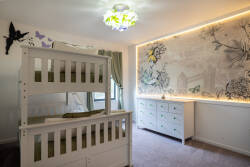 This charming children's bedroom, with its whimsical mural and soft lighting, features a cozy bunk bed and ample storage. The playful decor and delicate green accents create a cheerful space for your little adventurers.