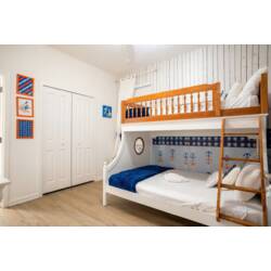 English, US:
Rest in a playful nautical-themed bedroom with a charming ship-style bunk bed, anchor wallpaper, blue accents, and warm wood floors. Soft bedding and fun details create a cozy space for kids to enjoy during vacation.
