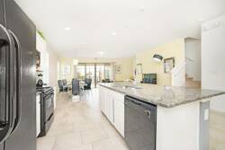 Bright and spacious, this kitchen features sleek black appliances paired with elegant granite countertops, creating a stylish cooking environment. The open layout seamlessly flows into the dining area, perfect for gatherings.