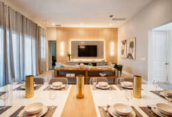 Experience a stylish dining area that combines comfort and sophistication, with a sleek table set for an elegant meal. The warm ambiance and soft gray plush seating create the ideal atmosphere for a relaxing evening.