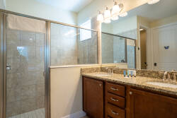 Experience this elegant bathroom with a spacious double vanity crafted from rich wood and a luxurious granite countertop. The glass-enclosed shower adds a modern touch, while natural light creates a soothing atmosphere throughout.