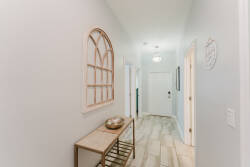 Enter a warm hallway with soft gray walls and light wood flooring, guiding you to inviting spaces. A decorative arch window adds charm, and a stylish console table reflects the thoughtful design that enhances your experience.