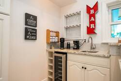 Experience the charm of this beautifully designed kitchen, where crisp white cabinetry meets a stylish breakfast bar with sleek black stools. Natural light fills the space, making it perfect for savoring your morning coffee.