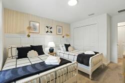 This cozy bedroom features two stylish beds dressed in crisp white and navy linens, offering a restful ambiance. The warm wood accents and soft lighting create a welcoming feel, perfect for unwinding after a day of adventure.