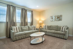 Relax in the cozy living room, where soft beige sofas invite you to unwind. The natural light streams through the elegant window treatments, highlighting the subtle textures of the decor and offering a warm, welcoming ambiance.
