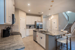 Enjoy culinary delights in this modern kitchen with shining granite countertops and bright white cabinets. Stylish bar stools encourage casual gatherings, while warm pendant lights create a welcoming atmosphere for evening meals.