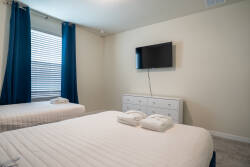 This cozy, bright bedroom offers two comfy beds with crisp white linens for your relaxation. Large windows with deep blue curtains let in natural light, while a sleek dresser provides ample storage for your belongings.