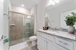 Enjoy this bright bathroom featuring sleek gray tiles and a spacious glass-enclosed shower for a modern touch. The stylish countertop and fresh greenery add warmth, making your daily routine feel like a special experience.