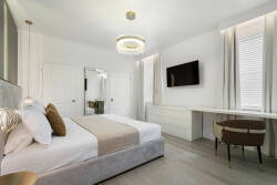 Experience luxury in this beautifully designed bedroom featuring a plush king-sized bed with soft linens and elegant pillows. Natural light enhances the chic decor, while a modern chandelier adds an inviting touch for relaxation.