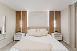 Experience a serene bedroom with a cozy plush bed dressed in soft linens and inviting pillows. Warm wood accents and gentle lighting create a relaxing atmosphere, while mirrored nightstands add a touch of modern elegance.