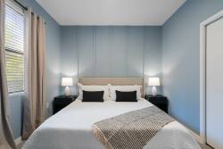Bathe in soothing hues of blue as you unwind in this cozy bedroom, where a plush queen bed awaits. The soft lighting from bedside lamps highlights the gentle textures of the bedding, offering a calm ambiance for restful nights.