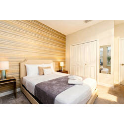 Rest in a bright bedroom with a comfortable bed, soft white bedding, striped accent wall, neutral curtains, bedside lamps, carpeted floor, and warm modern decor.