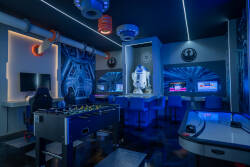 Enjoy our lively game room, where sleek black furnishings and bright blue lighting set an exciting vibe. Have fun with foosball matches or jump into interactive gaming at stylish stations adorned with cool pop culture decor.