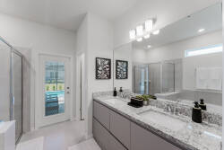 This bright and airy bathroom boasts a sleek granite countertop and modern cabinetry, creating a stylish and functional space. Enjoy the natural light from the glass door that opens to a lovely outdoor area.