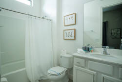 Bright and airy, this bathroom features a clean white palette complemented by framed botanical prints that add a touch of charm. The spacious mirror reflects natural light, creating a refreshing atmosphere for your daily routines.
