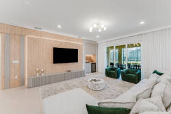 Experience comfort in this stylish living room with a plush white sectional and vibrant green chairs. Large windows invite natural light and views of the outdoors, while warm wood accents add a cozy touch to your stay.