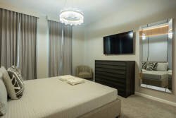 Relax under the soft glow of the chandelier in this cozy bedroom, complete with a plush bed and elegant dark wood furniture. Enjoy the carefully selected decor and natural light that create a stylish retreat for your stay.