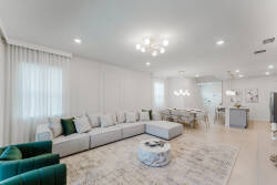 Enjoy the warmth of natural light in this spacious living area, where a cozy sectional invites you to relax amid soft neutral walls and a stylish chandelier that adds elegance, creating a welcoming atmosphere for all guests.