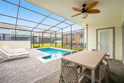 Enjoy a private screened pool area with lounge chairs, covered patio dining, ceiling fan, and open sky views, perfect for swimming, relaxing, and family meals during vacation.